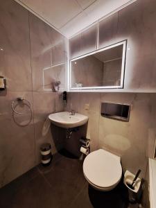 a bathroom with a white toilet and a sink at Hotel Augustin Komfort Leipzig in Leipzig