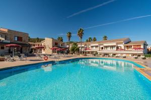 a large swimming pool in a resort with chairs and umbrellas at Club Esse Posada in Palau