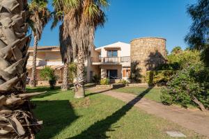 a house with palm trees in front of it at Club Esse Posada in Palau