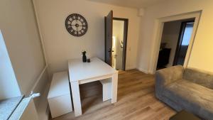 a living room with a table and a clock on the wall at Am Gebirgsbad in Kurort Jonsdorf