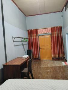 a bedroom with a desk and a bed and a door at Keluncing Field Homestay in Kotaraja +7 photos