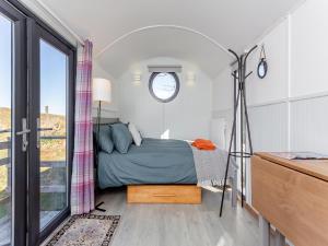 a small bedroom with a bed and a window at Shepherds Hut - Uk49096 in Inchnadamph