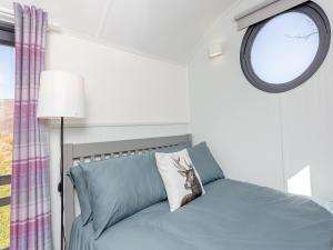 a bedroom with a bed and a round window at Shepherds Hut - Uk49096 in Inchnadamph +6 photos