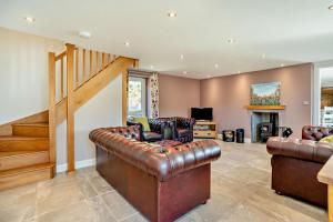 a living room with leather furniture and a staircase at 3 Bed in Defynnog oc-p33133 in Devynock