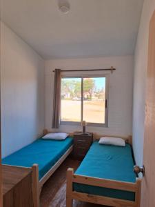 two beds in a room with a window at Tamara in La Paloma