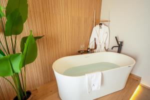a bath tub in a bathroom with a plant at Agorà Luxury Experience in Zafferana Etnea