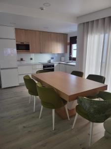 a kitchen with a wooden table and green chairs at Casa do Azeite in Torre de Moncorvo