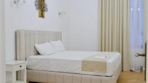 a bedroom with a white bed with a stool on it at Vila BELVEDERE in Brăila