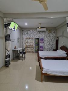 a room with two beds and a table and a tv at Abi Hotel & Rastaurant in Jaffna
