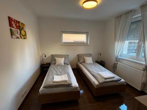 two beds in a room with two windows at Maxi Apartman in Budaörs