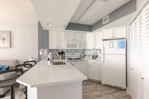 a kitchen with white cabinets and a white refrigerator at Oceanview Modern 1BR, king bed at Carolinian Resort" in Myrtle Beach