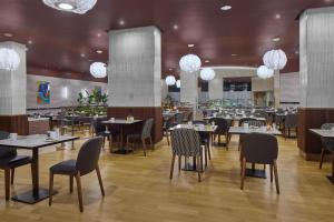 a restaurant with tables and chairs and chandeliers at Hilton Milan in Milan