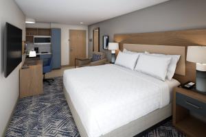 a hotel room with a large bed and a kitchen at Candlewood Suites Beachwood Cleveland by IHG in Beachwood