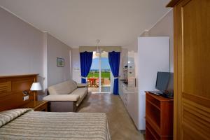 Santa Monica Resort في لا كاستيلا: غرفة نوم بسرير واريكة وتلفزيون