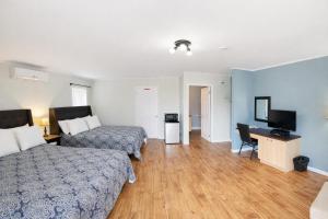 a hotel room with two beds and a desk and a television at Motel Au Vieux Frontenac in Thetford Mines