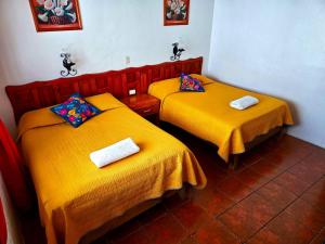 two beds in a room with yellow sheets at Hotel San Luis in San Cristóbal de Las Casas