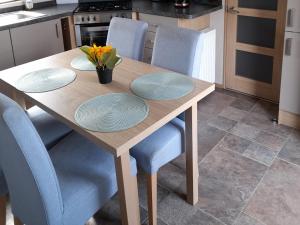 a wooden table with four blue chairs and a kitchen at Yew in Denny