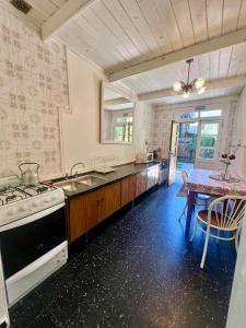 a kitchen with a stove and a sink and a table at Departamento Céntrico 3 in El Bolsón
