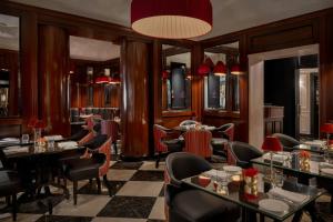 a restaurant with tables and chairs and a chandelier at Hotel d’Inghilterra Roma – Starhotels Collezione in Rome