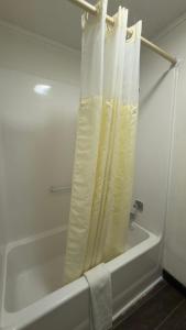a white bath tub with a shower curtain in a bathroom at Executive Inn in Warner Robins