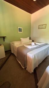 a bedroom with two beds in a green wall at Pousada Lua Nova in Paraty