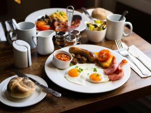 a table with plates of breakfast food on it at Hitchin Priory Inn in Hitchin