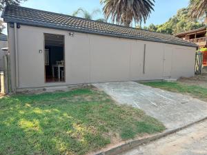 a white building with a door in a yard at Uys Cottage on 79 in Heidelberg