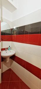 a bathroom with a white sink and red and white tiles at Alex City Apartment Gabrovo in Gabrovo +11 photos