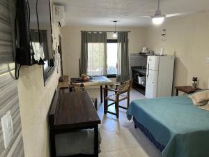 a room with a bed and a table and a kitchen at Departamento para 2 pers con vista a las sierras OC in Villa Giardino
