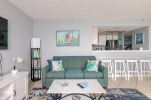 a living room with a green couch and a kitchen at Oceanfront 2BR King Suite Atlantica Resort in Myrtle Beach
