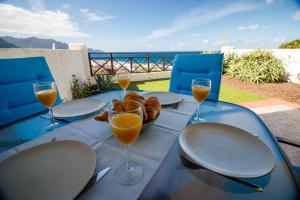 una mesa con platos y vasos de zumo de naranja y pan en Casa Julia en Agaete