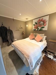 a bedroom with a large bed and a painting on the wall at Uys Cottage on 79 in Heidelberg