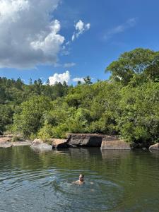 a man swimming in the water in a river at Kombi Home in Piedade