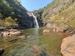 a river with a waterfall in the middle of a canyon at Kombi Home in Piedade +22 photos