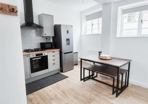 a kitchen with a table and a stainless steel refrigerator at Cosy & Luxury 2BR Flat in Calverton in Calverton +24 photos