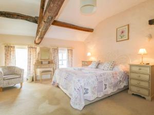 a bedroom with a bed and a chair and windows at The Farmhouse in Keswick