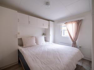 a bedroom with a bed with white sheets and a window at Ermmoon Cottage in Erm
