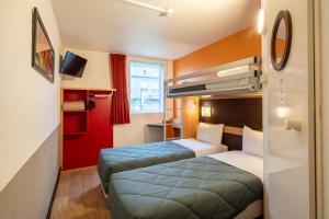 a hotel room with two beds and a tv at Premiere Classe Roissy Aéroport Charles De Gaulle in Roissy-en-France