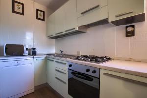 a kitchen with white cabinets and a stove top oven at 20 passi dalla spiaggia - Panoramic Duplex in Porto Rotondo