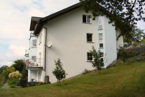 una casa blanca en una colina con árboles delante de ella en Pension Garni Haus Bismarckhöhe en Bad Ems