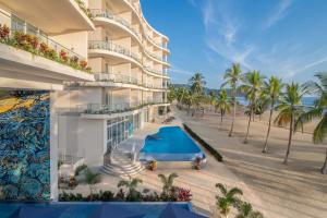 an exterior view of a resort with a pool and palm trees at Clarita's Beach Bar & Resort, WorldHotels Elite in Jacó