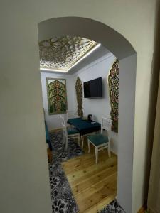 a living room with a table and chairs and an archway at Olimxon Guest House in Bukhara