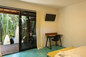 a bedroom with a bed and a desk and a balcony at La Punta SurfHouse in Brisas de Zicatela