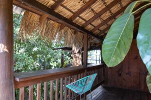 a wooden porch with a chair and a palm leaf at La Punta SurfHouse in Brisas de Zicatela
