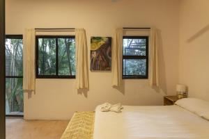 a bedroom with a bed and two windows at La Punta SurfHouse in Brisas de Zicatela