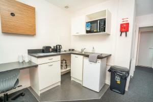a small kitchen with white cabinets and a microwave at Spacious & Bright Central Coventry Budget Studio in Coventry