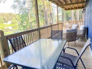 a table and chairs on a porch with a view of a lake at Big Bass Bungalow - Quitman Tx in Quitman
