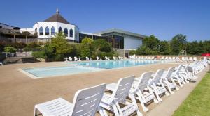 a row of white chairs next to a swimming pool at Hoburne Devon Bay - Hot Tub 2 Bed Paignton in Paignton