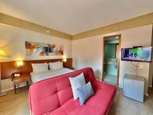 a hotel room with a red couch and a bed at Flat Borges Lagoa com vaga de garagem, UH412 in São Paulo