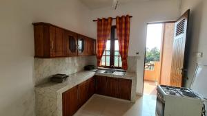 a kitchen with wooden cabinets and a sink and a window at Oceanway Residences in Wattala